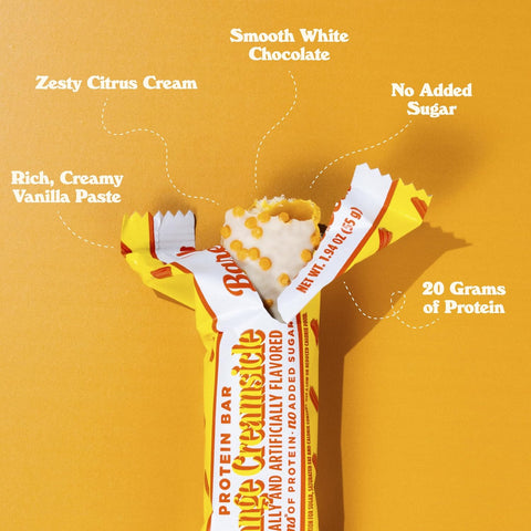Baton proteinowy Guiltfree Barebells Orange Creamsicle w białej polewie z pomarańczową posypką na żółtym tle
