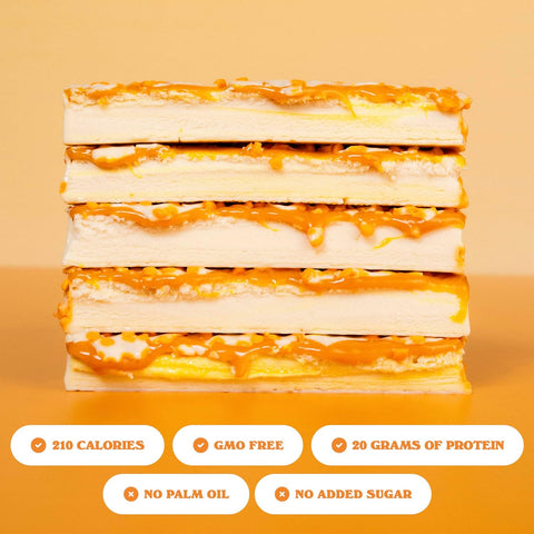 Stos batonów proteinowych Guiltfree Barebells Orange Creamsicle w białej polewie z pomarańczową posypką