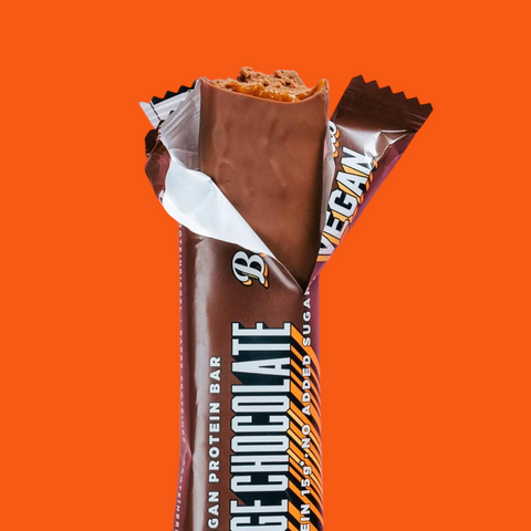 Guiltfree wegański baton proteinowy Barebells Orange Chocolate w czekoladowej polewie z nadzieniem na różowym tle