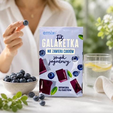 Guiltfree Emix Fit galaretka jagodowa bez cukru w opakowaniu 25g obok miseczki świeżych jagód i szklanki wody