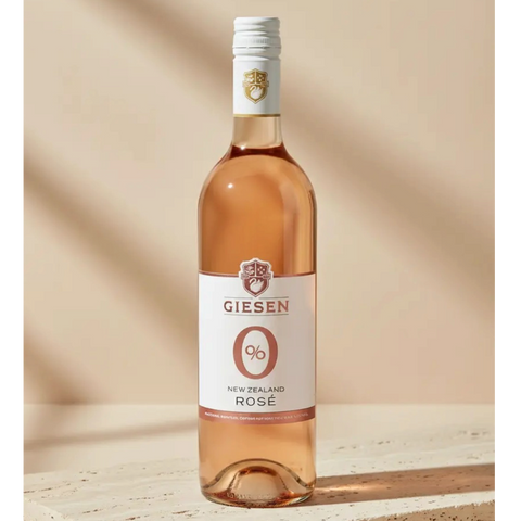 Butelka bezalkoholowego wina różowego Guiltfree Giesen 0% Rosé o jasnoróżowej barwie na beżowym tle