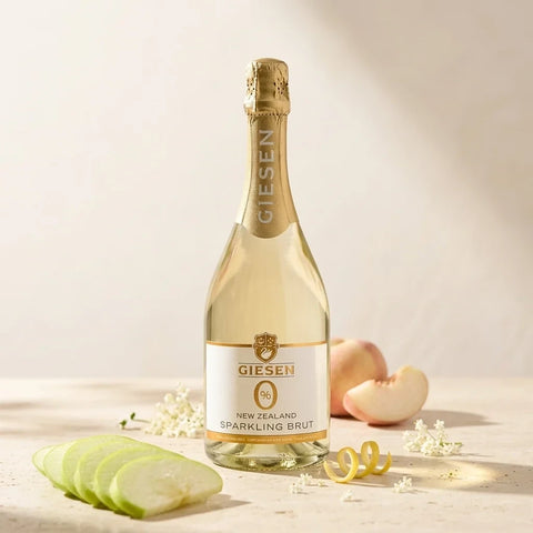 Butelka bezalkoholowego wina musującego Guiltfree Giesen Sparkling Brut z jabłkiem, brzoskwinią i kwiatami w tle
