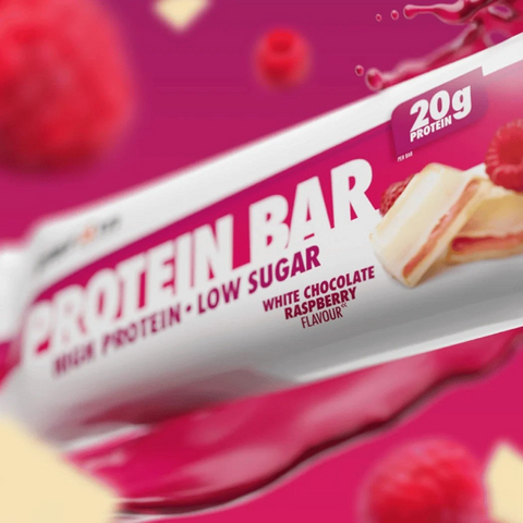 Baton proteinowy Guiltfree Per4m o smaku białej czekolady i malin z 20g białka w opakowaniu na różowym tle