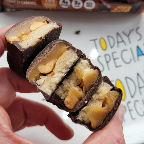 Guiltfree Quest Nutrition Peanutty Caramel protein bar pieces showing layers of chocolate, caramel, and peanuts.
