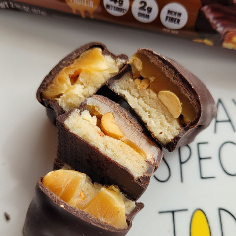 Guiltfree Quest Nutrition Peanutty Caramel protein bar pieces showing layers of chocolate, gooey caramel, and peanuts.