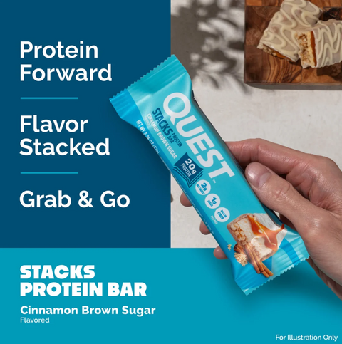 Guiltfree baton proteinowy Quest Stacks o smaku cynamonki z brązowym cukrem trzymany w dłoni na tle deseru